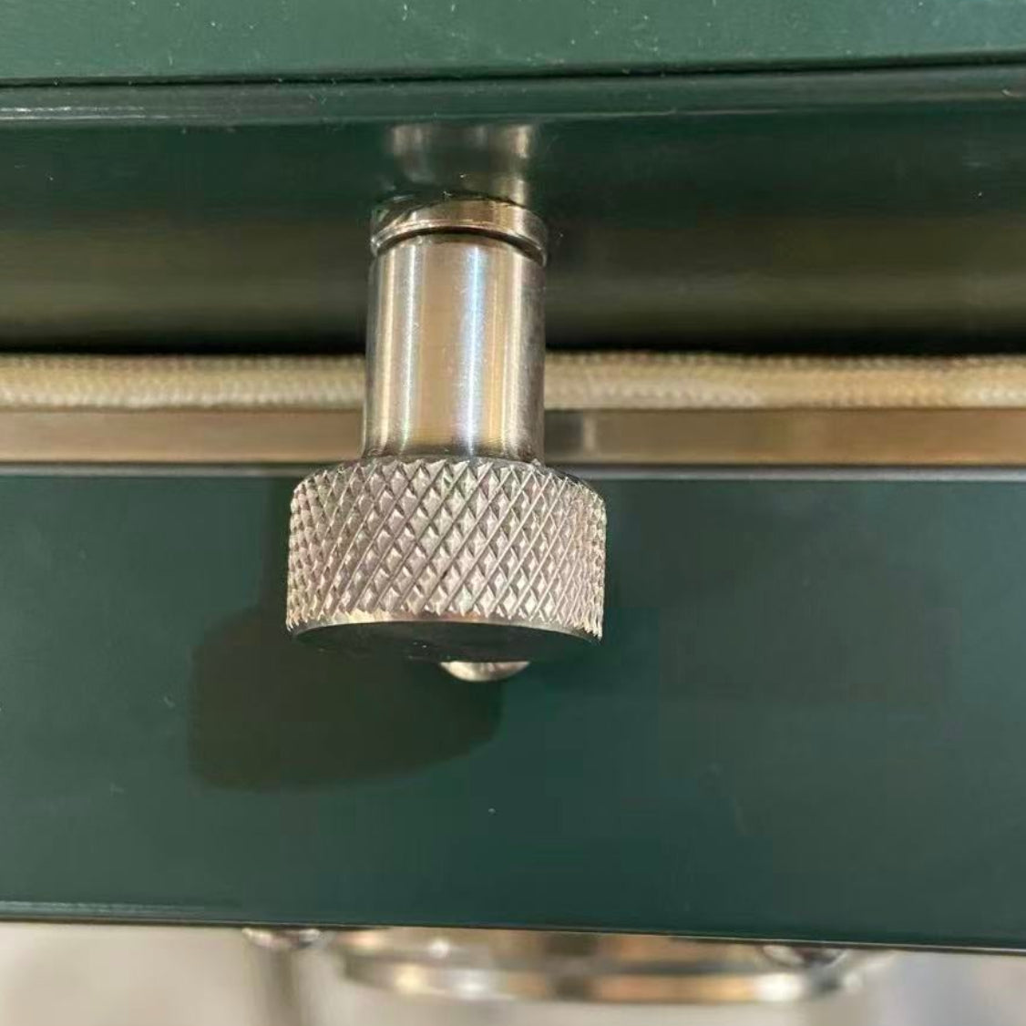 Close-up of a metallic air vent knob on a green surface