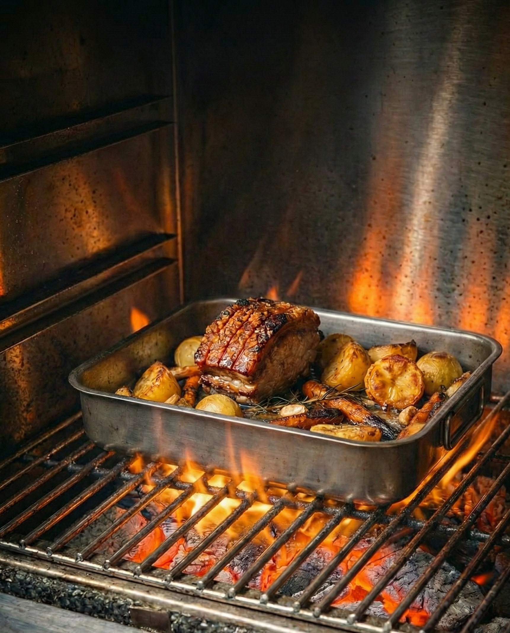 Roasted meat and vegetables in a pan over an open flame in a stack.